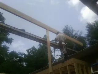 Carpenter setting a ridge beam over a new addition frame in Spencer